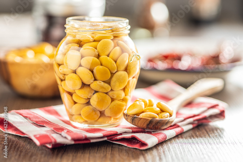 Lupini beans in brine. Pickled lupin in jar on kitchen table. photo