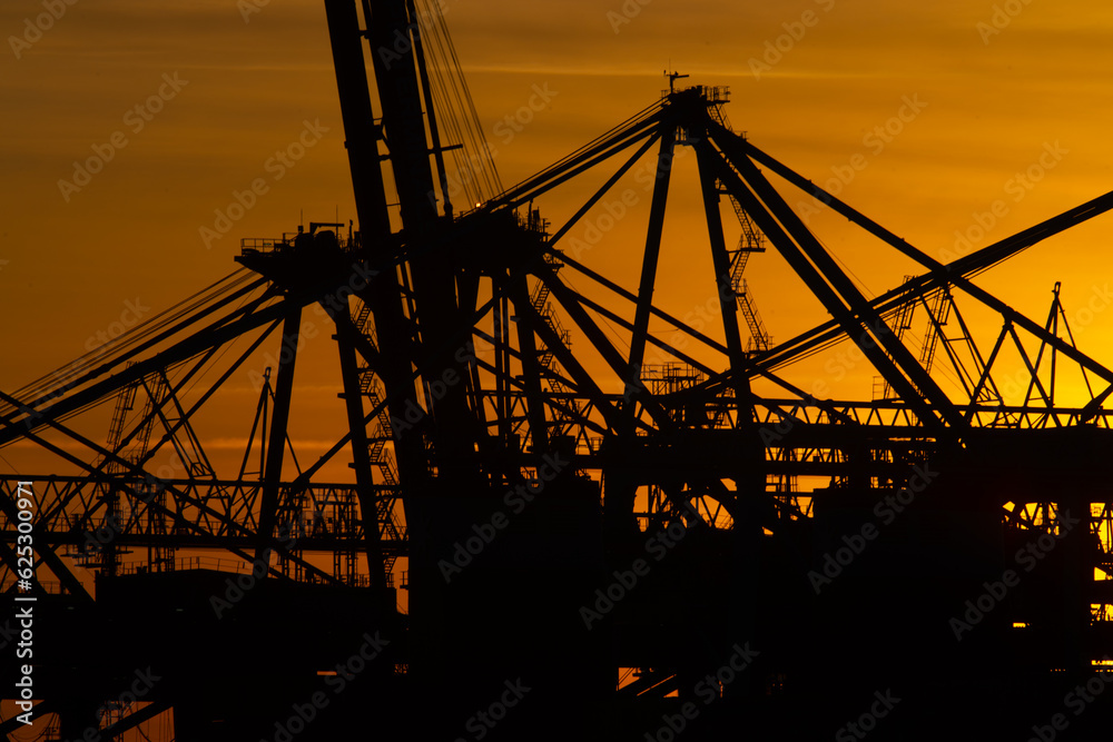Details of gigantic container gantry cranes at sunset.