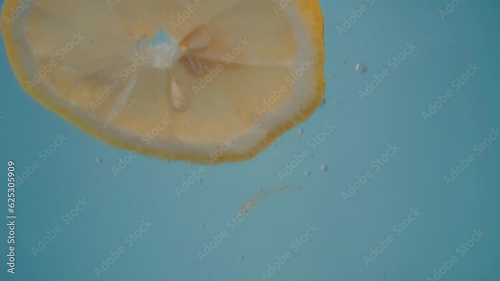 Slow Motion Shot of Water with lemon Slices. Close-up of falling ripe lemon into water. Citrus fruits. Clean water. Slow Motion Shot of Water with lemon Slices. Close-up of falling ripe lemon into water. Citrus fruits. Clean water.