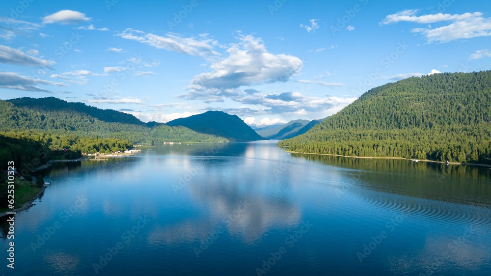 Aerial view of Teletskoye lake in the Altai Mountains in summer. Coniferous forest, blue sky with clouds. Russian siberia scenery. Artybash. Altai Republic
