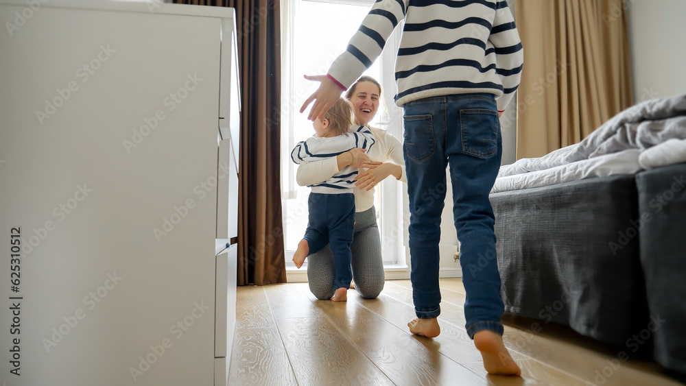 Two little boys runs down a long wooden corridor towards their's mother's warm embrace. Love and happiness that can be found within a family home.