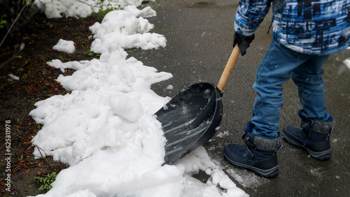 Young boy can be seen shoveling snow from the backyard or walkway after a snowstorm or blizzard. Concept of responsibility, winter maintenance, and child development.