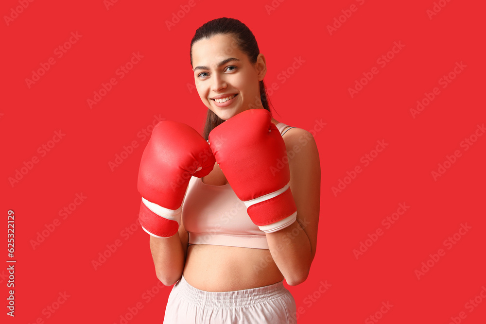 Young woman with boxing gloves on red background Young woman with boxing gloves on red background