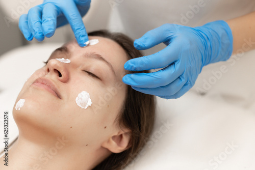 Woman receiving face treatment by cosmetologyst in beauty salon