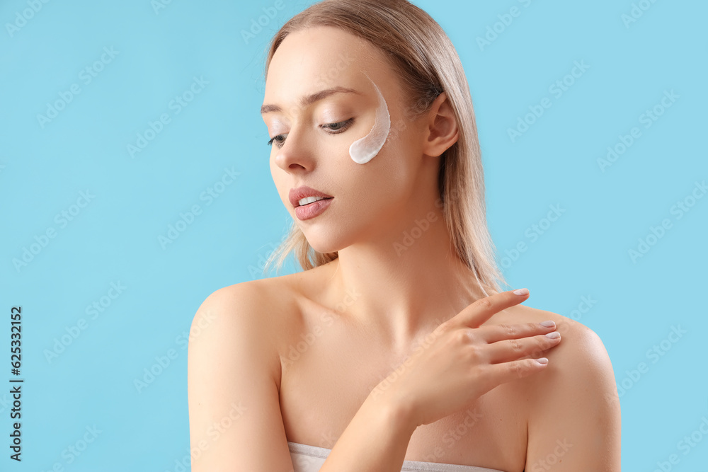 Pretty young woman with cream on her face against blue background Pretty young woman with cream on her face against blue background