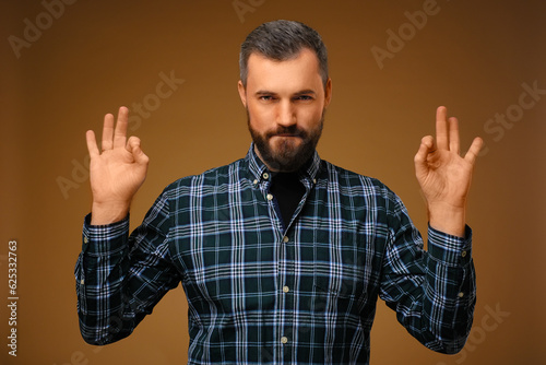Handsome man with beard.Plaid shirt. Shows okay with two hands.