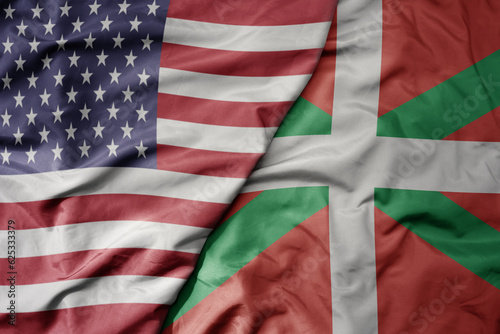 big waving colorful flag of united states of america and national flag of basque country .