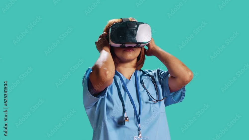 Healthcare professional wearing virtual reality headset remotely checking patient. Nurse isolated over blue studio background using high-tech advanced clinical vr gadget, close up Healthcare professional wearing virtual reality headset remotely checking patient. Nurse isolated over blue studio background using high-tech advanced clinical vr gadget, close up