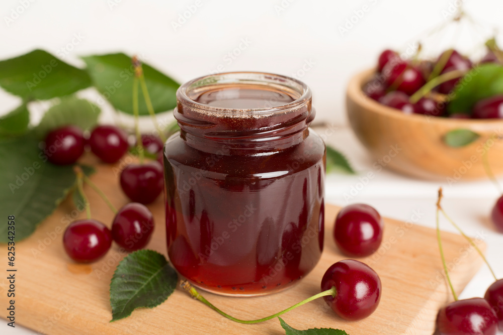 Jar with tasty homemade cherry jam on wooden table Jar with tasty homemade cherry jam on wooden table