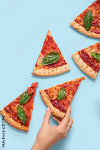 Woman taking slice of tasty pizza on blue background