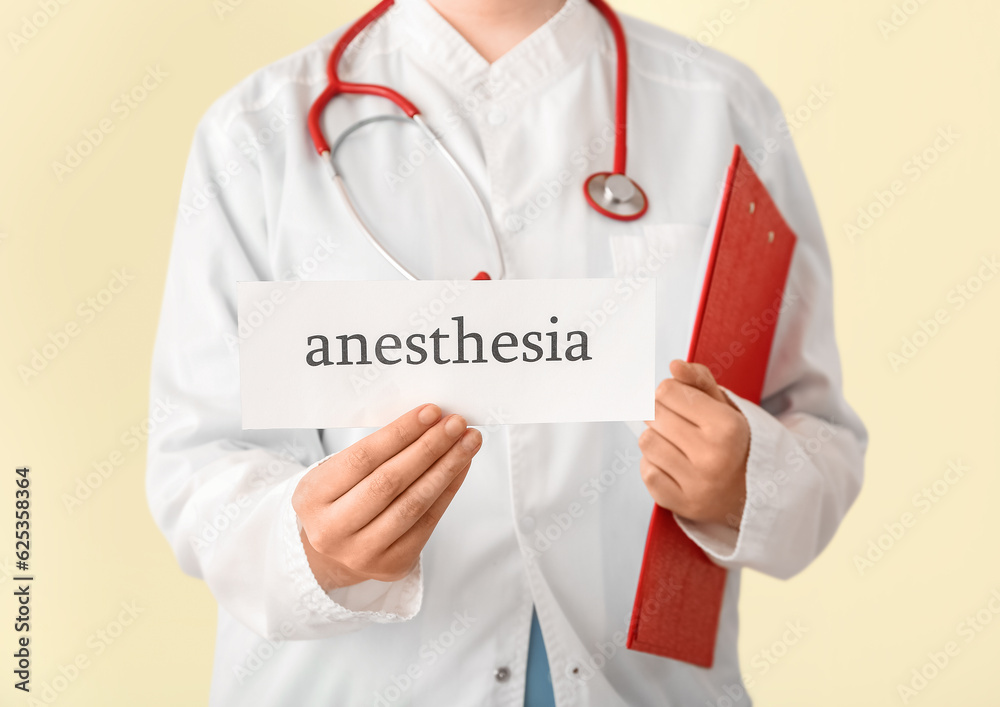 Female doctor holding paper with word ANESTHESIA on beige background, closeup Female doctor holding paper with word ANESTHESIA on beige background, closeup