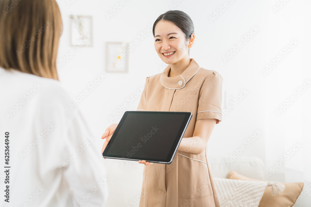 エステサロン・ネイルサロンでお客様にメニューの説明をする女性（タブレットPC）
