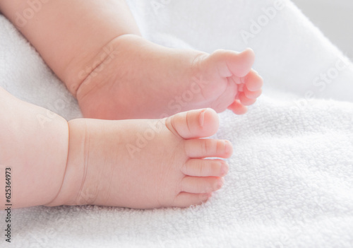 Tiny newborn baby feet closeup on a white blanket