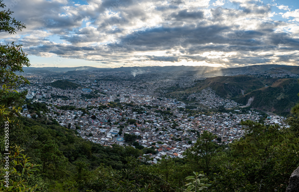 Panoramic View of Tegucigalpa City with Hills, Houses, Buildings, and Trees Surrounded by Green Mountains on a Cloudy Day