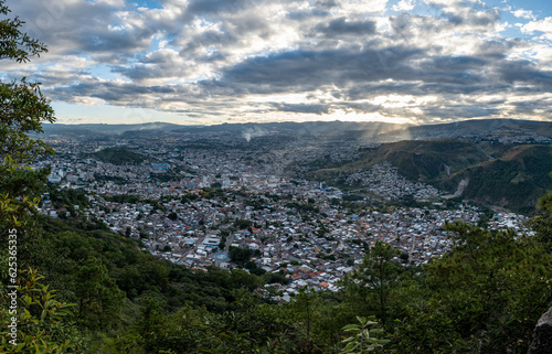 Obraz na płótnie Panoramic View of Tegucigalpa City with Hills, Houses, Buildings, and Trees Surrounded by Green Mountains on a Cloudy Day w salonie
