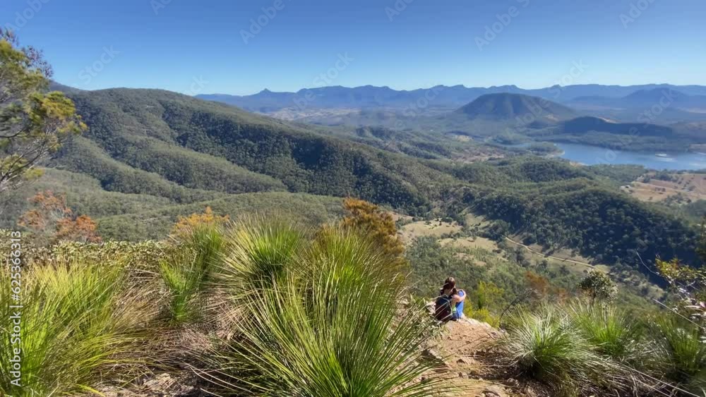 hiker girl sitting on the top of mount may admiring panorama of mountains and lake maroon; dangerous hike in south east queensland, australia hiker girl sitting on the top of mount may admiring panorama of mountains and lake maroon; dangerous hike in south east queensland, australia