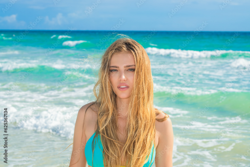 Portrait of young woman in bikini on the tropical beach. Sexy woman having fun at beach. Summer portrait of young beautiful girl on beach with bikini. Beautiful young woman on the beach.