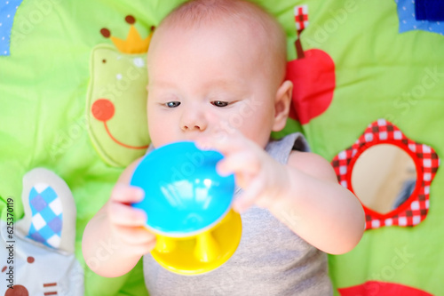 Little baby play with bright rattle toy. Educational toys for childs