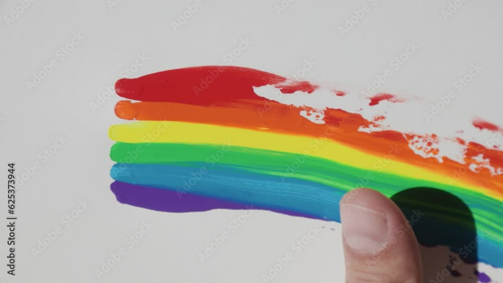 LGBT design, rainbow flag, Close-up of a man's hand smearing drops of acrylic paints on a white sheet of paper. lesbian, gay, bisexual, transgender social movements. Rainbow. Artistic watercolor