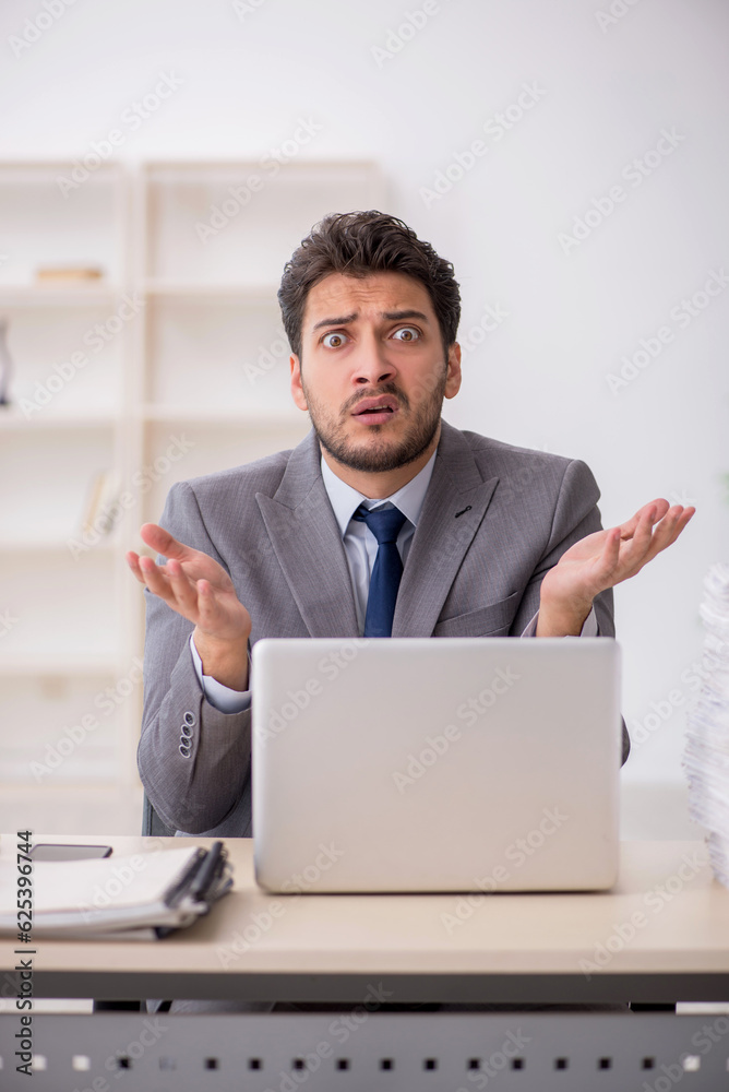 Young male employee and too much work in the office Young male employee and too much work in the office