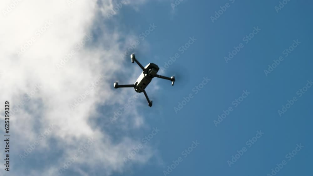 Quadrocopter against a background of blue sky and clouds. Unmanned aerial vehicle UAV in the sky. Modern drone for surveillance, travel and work. Blurred video Quadrocopter against a background of blue sky and clouds. Unmanned aerial vehicle UAV in the sky. Modern drone for surveillance, travel and work. Blurred video