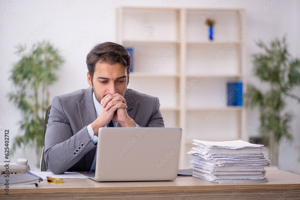 Young male employee and too much work in the office Young male employee and too much work in the office