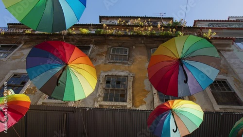 Looking At The Rainbow Umbrellas Floating Over The Streets Of Calle Rosa In Lisbon, Portugal. Low Angle