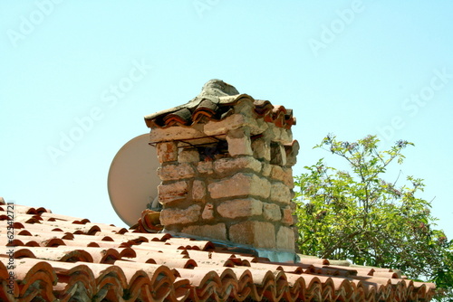 Balchik, Dobrich region, Bulgaria - 07.30.2014. A chimney and a TV antenna on a red tiled roof photo