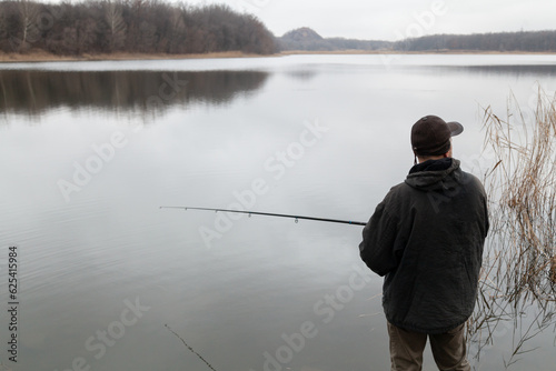 fisherman in a cap catches fish on the river bank....