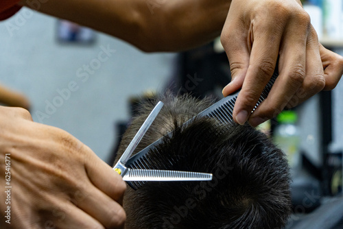 with a hairdressing scissors a barber man cutting