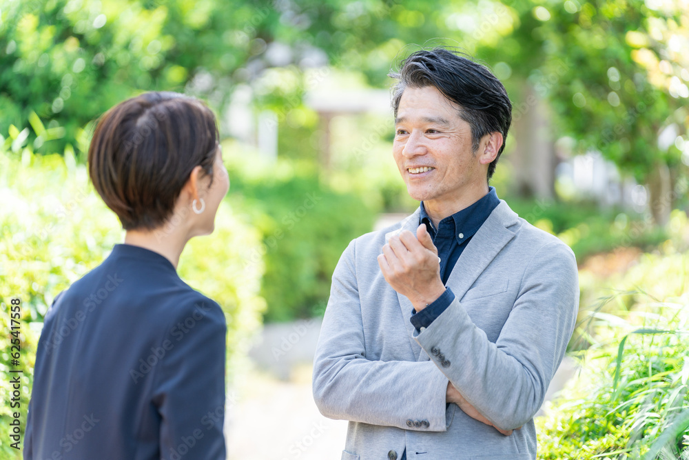 屋外の新緑の前に立つビジネスマンたち