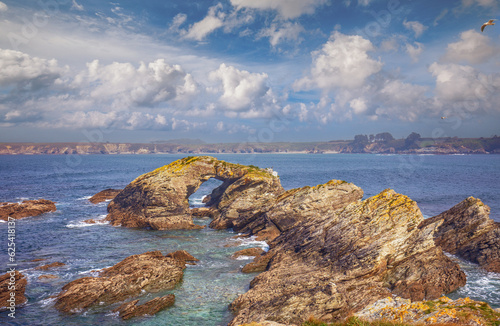Seascape with the rocky shore in spring. View of Ria de Ribadeo del Eo bay. Rock with the natural arch. Ribadeo, Spain photo