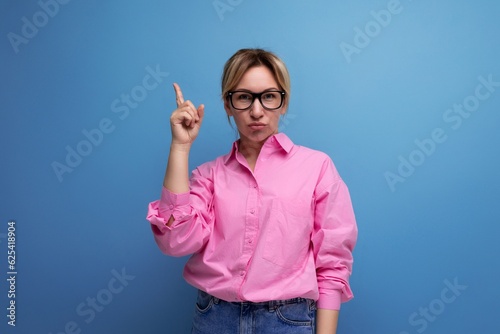 young charismatic caucasian blond leader careerist woman with ponytail with glasses dressed in a pink blouse on a studio isolated background with copy space