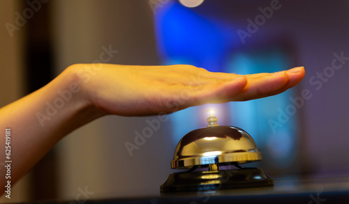 Female hand ringing in service bell on wooden table