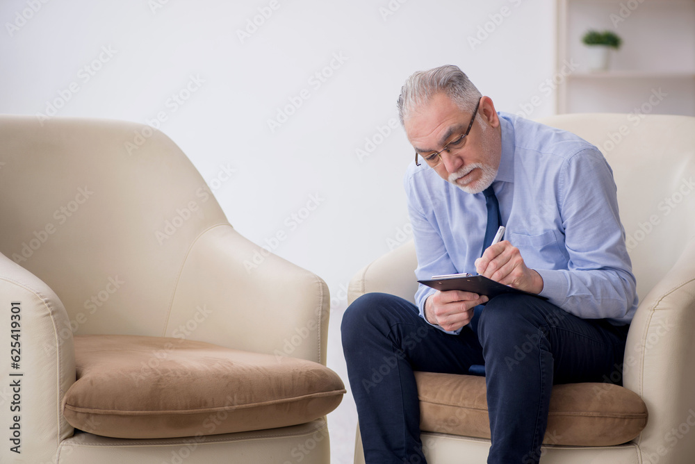 Old male psychologist sitting in the room