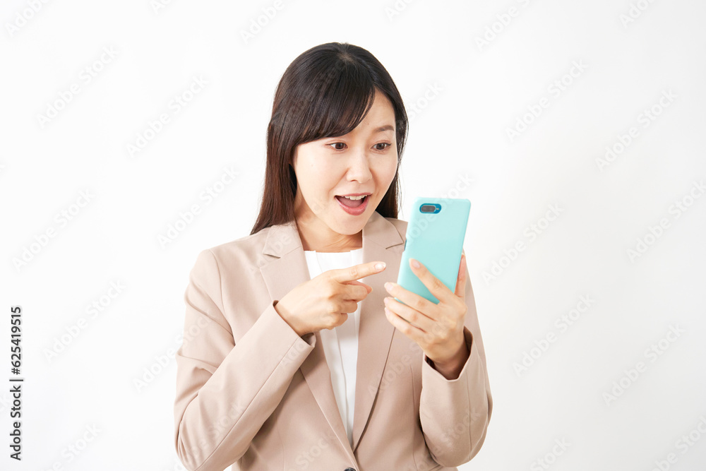 スマートフォンを見て驚くミドルエイジのビジネスウーマン 白背景 スマートフォンを見て驚くミドルエイジのビジネスウーマン 白背景