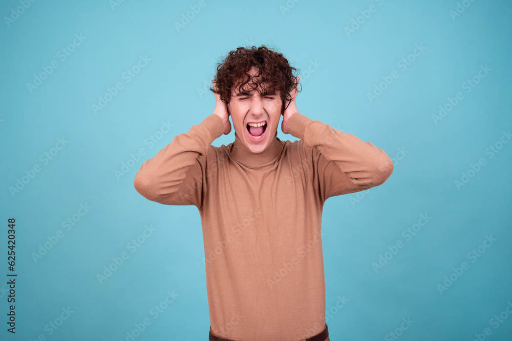 Emotional guy is surprised, happy and sad posing in the studio on a blue background. Emotional guy is surprised, happy and sad posing in the studio on a blue background.