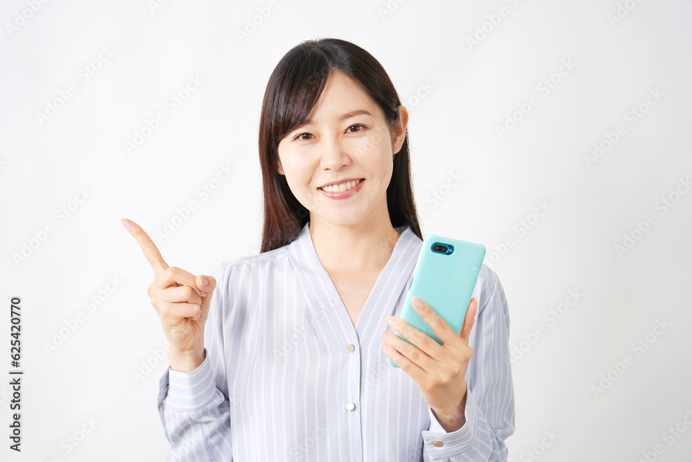 スマートフォンを持って左側を指差すミドルエイジの女性 スマートフォンを持って左側を指差すミドルエイジの女性