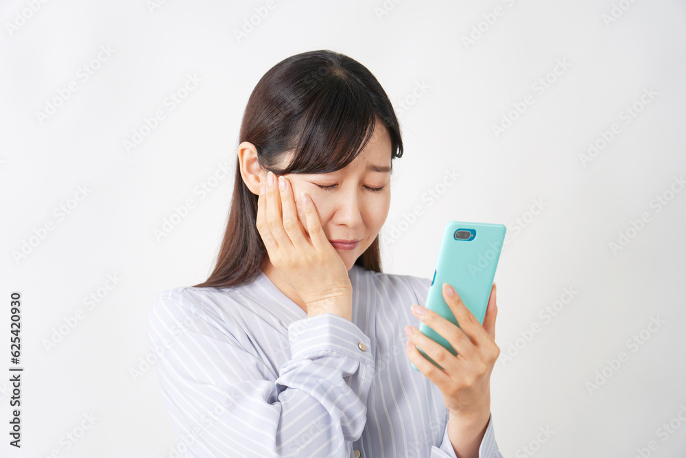 スマートフォンで電話するスマートフォンを持って悲しむミドルエイジの女性　白背景