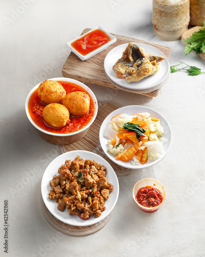 A food menu consisting of meat, eggs, tempeh orek, vegetables and chili sauce served on the table