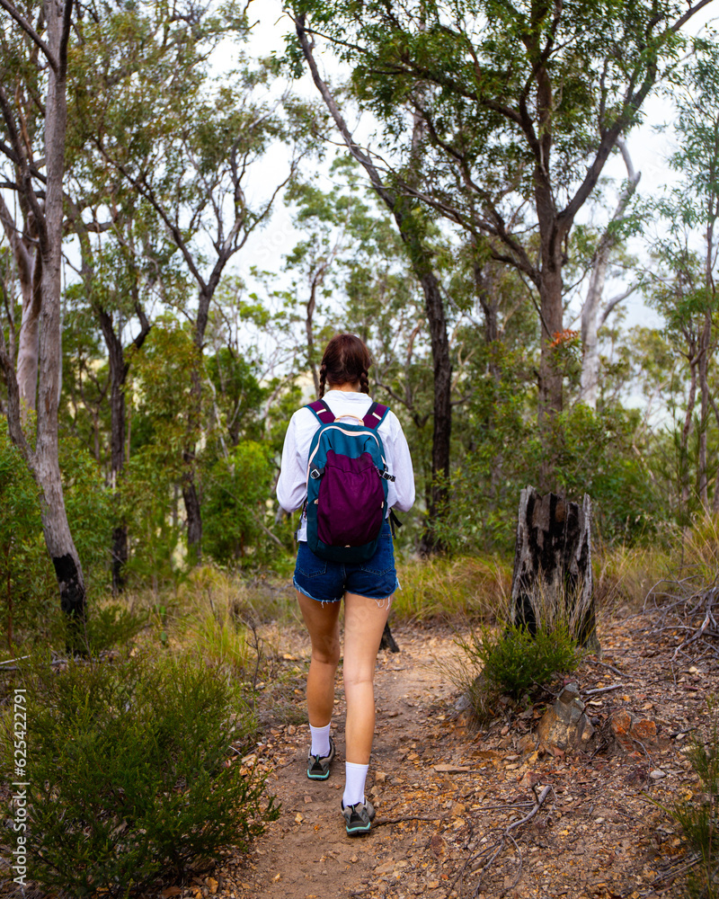 beautiful girl with backpack hiking through dense bush in mount barney