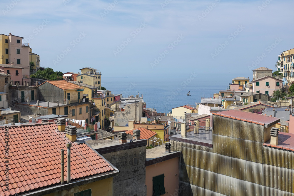 Cinque Terre, Italy - view of the sea and roofs of colorful houses in Riomaggiore, a seaside town on the Italian Riviera. Summer travel vacation background. Postcard from Europe. Italian architecture.