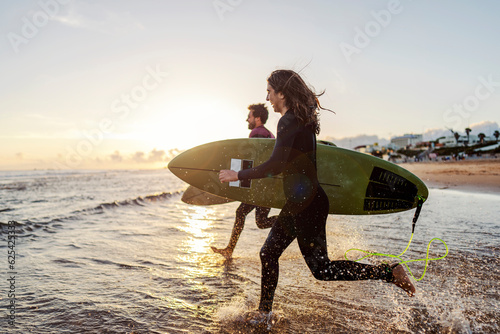 Photography Friends rushing to water with surfboards.