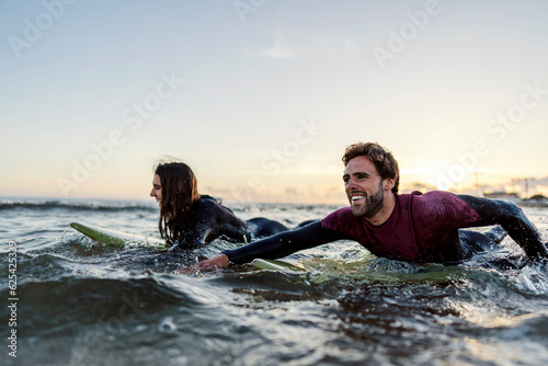 Photography Surfers with boards swimming in ocean.