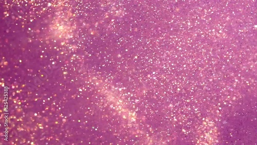 Golden Dust Particles Motion In Violet Fluid. Gold particles moving background. Abstract backdrop of natural glitter sparkling sequins floating in liquid.