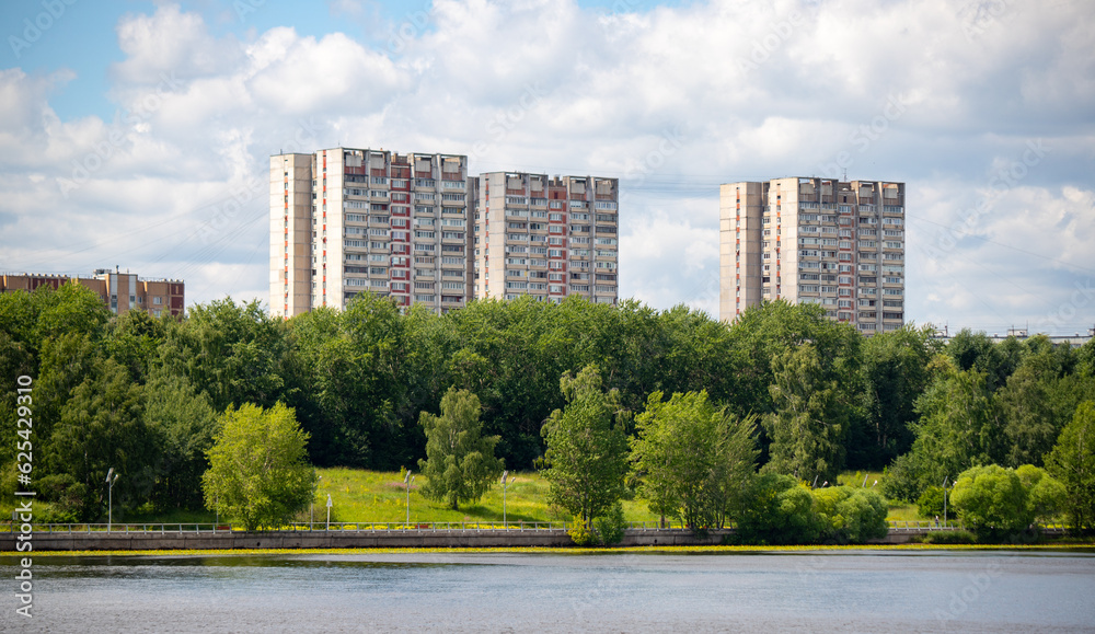Multi-storey buildings in the green zone of the park against the sky.