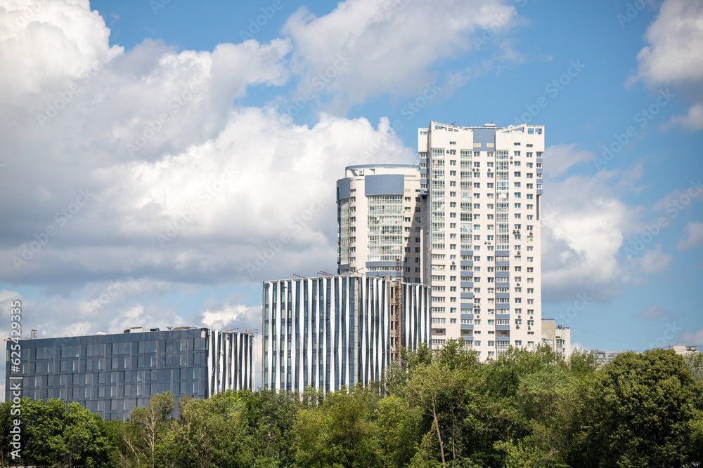 Multi-storey buildings in the green zone of the park against the sky.