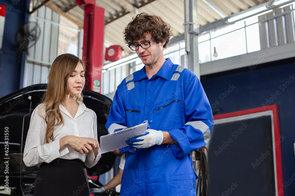 Fototapeta premium Man garage worker and woman customer talking to discuss the details of car repairs. male mechanic holding clipboard and writes down repair list for female client. 
