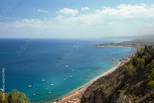 Photograph of the coast of Taormina in Sicily, houses, boats and trees.