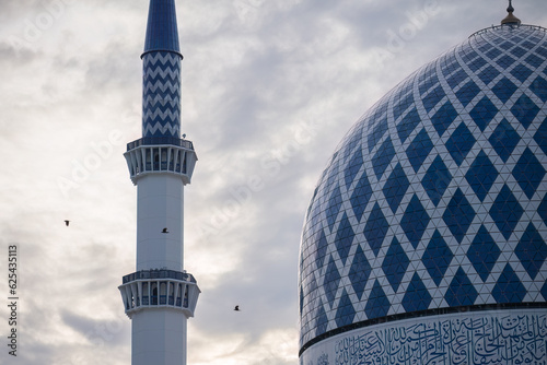 Tableau sur toile Birds flying through the dome of the blue mosque on cloudy evening